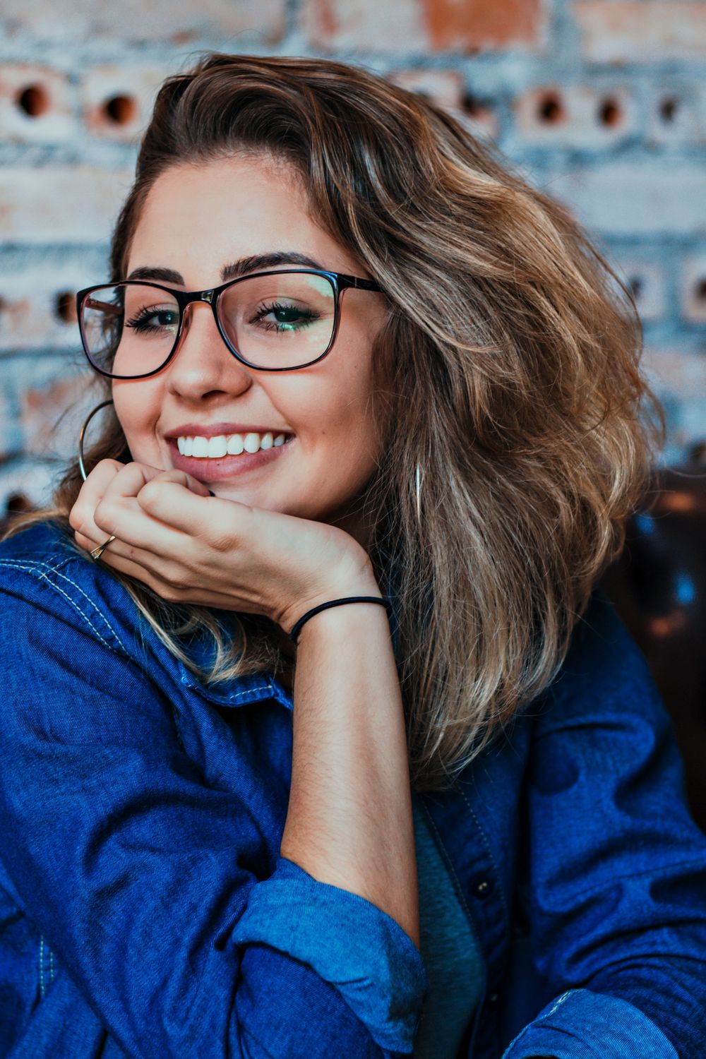 Priya, smiling in glasses and a denim shirt